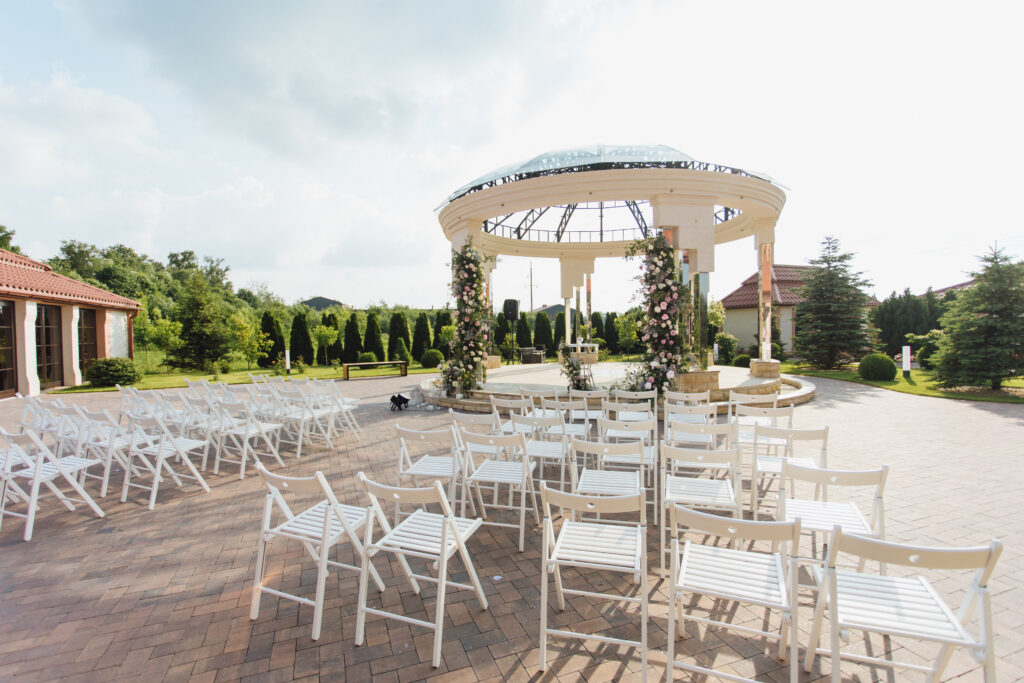 Outdoor wedding ceremony with white chair rentals and floral arch setup at elegant venue in Redwood City California